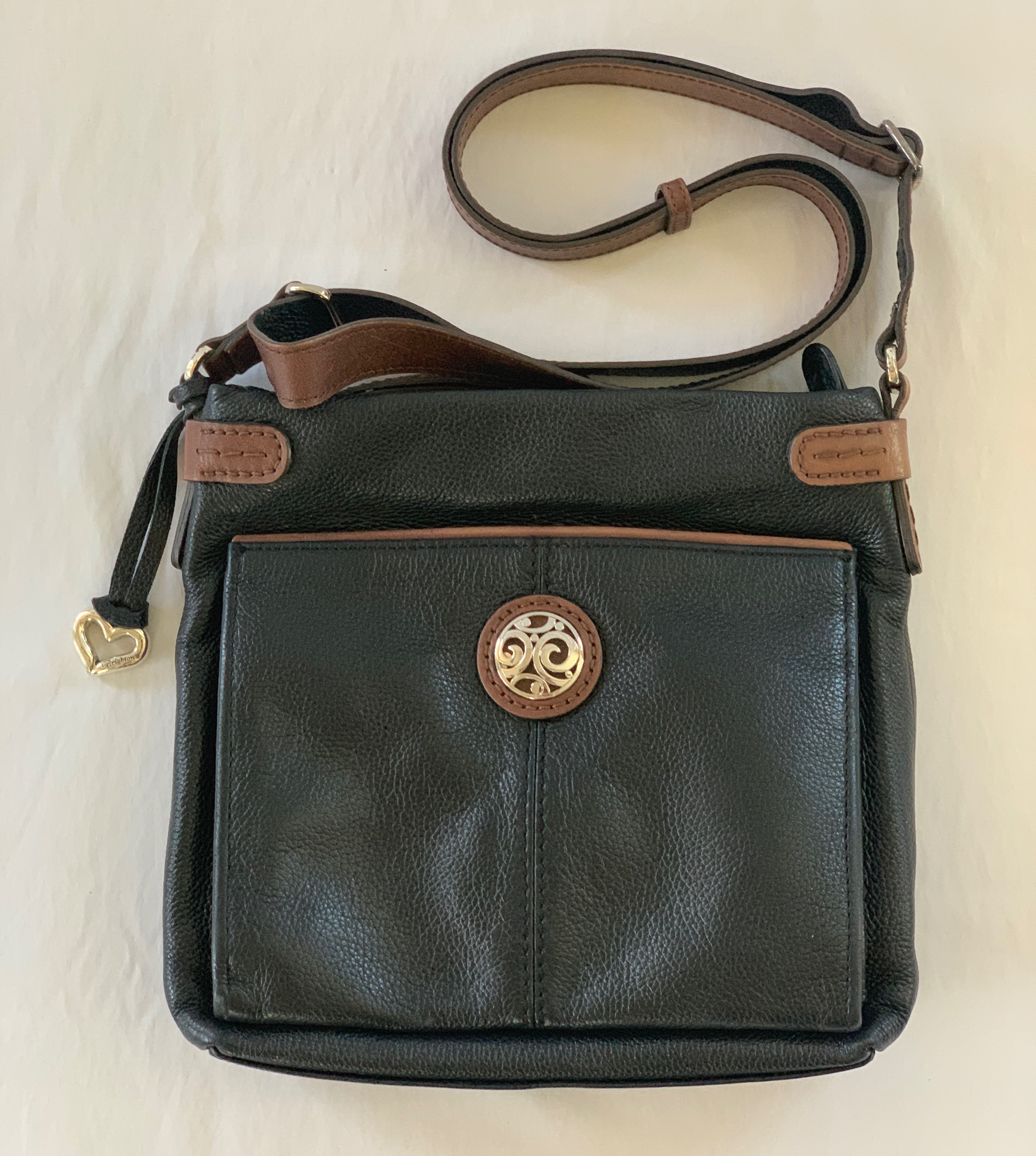 Black leather shoulder bag with brown accents and silver pendant. Interesting full pull out front pocket lined with complete wallet accessories. Great condition.