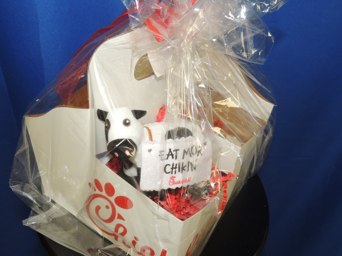 A Chik Fil A gift basket with a cute mug, plush cow, some Chik Fil A accessories and a $100 gift card.