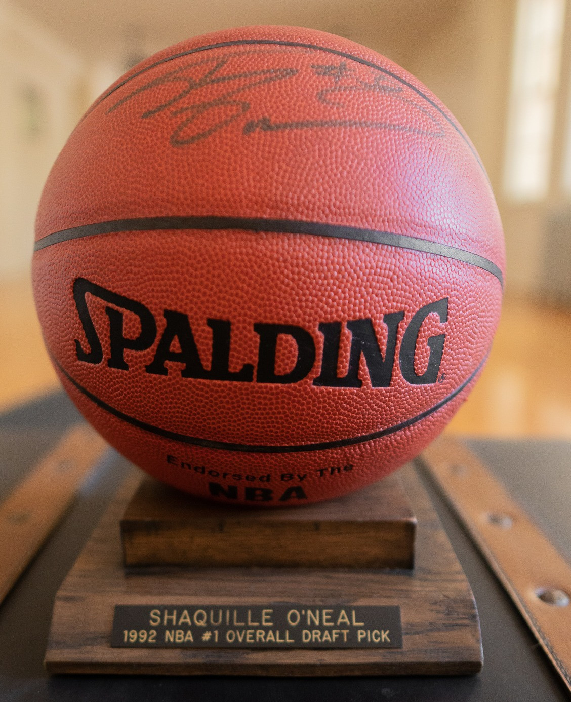 Spalding basketball autographed by Shaq. A wooden stand with an engraved plaque that reads " Shaquille O'Neal, 1992 NBA #1 Overall Draft PIck" is included.