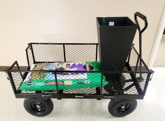 A MASSIVE garden cart, some garden tools, a bag of fertilizer, gloves and a planter box.