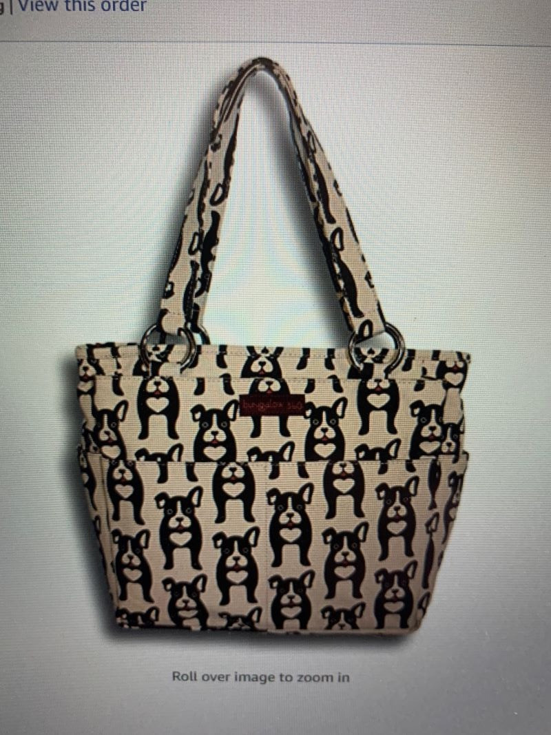 Bungalow 360 Pocket Bag - Dog Design - Natural durable cotton canvas. 100% Vegan. Polka dot lining. Measures 10" H x 11" W x 4.5" D. Strap drop length is 9". Interior features one main compartment (zipped closure with signature peace sign zipper pull), 2 side velcro compartments. One-of-a-kind patterns. Bungalow 360 is renowned for its whimsical animal themed prints. Each print has copyrights which means you will not find them anywhere else.