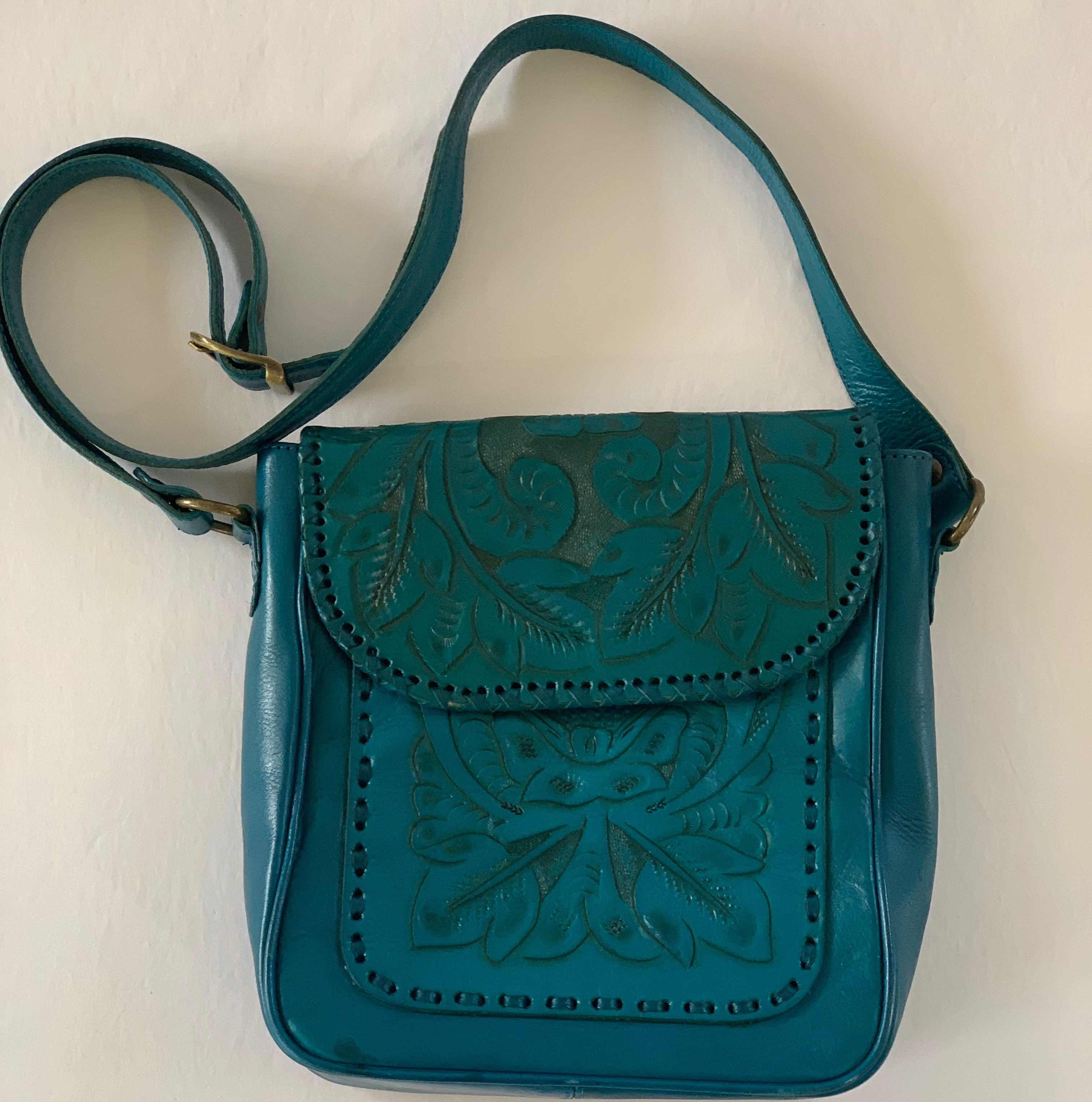 Teal leather embossed crossbody bag. Exterior has some ink marks, interior some staining.