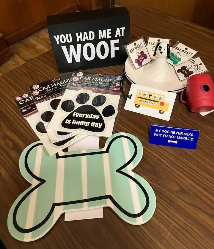 Includes Country Club Animal Clinic gift certificate redeemable for grooming, blueberry facial, pawdicure, 4x6 picture or one day at Daycare (valid for large-extra large dogs or smaller),  bone ceramic decor, paw magnets, “You had me at Woof” wall decor, Obedience school label tag, ceramic doggie ring dish, quirky dog tags, poop bag dispenser and "My Dog Never Asks Why I'm Not Married" desk sign..