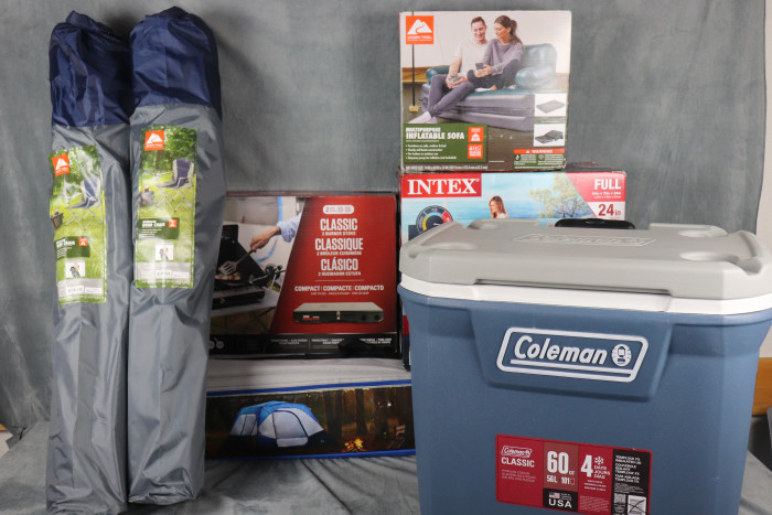 Cooler is a 60-quart cooler that holds up to 50 cans and 27 pounds of ice for four days, features heavy-duty wheels and molded cup holders, and doubles as a 250-pound seat.
Inflatable Air Couch  converts into five different seating or sleeping configurations, features a sturdy coil beam structure, and deflates for compact storage.
Camping Chairs are blue and gray foldable chairs designed for camping.
Coleman Table Top is a compact 2-in-1 propane grill and stove combo features a dual-burner design to cook meals and grill food simultaneously at your campsite.
Cabin Tent is a spacious cabin tent features pre-attached poles for fast setup, fits up to six campers, and includes mesh windows, storage pockets, and built-in LED lighting.
