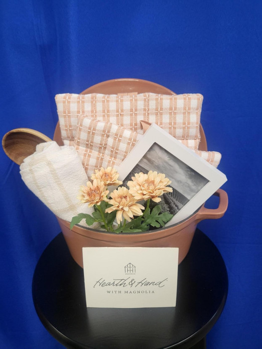 A beautiful Dutch oven with some Oven Mits, a towel and a picture frame.