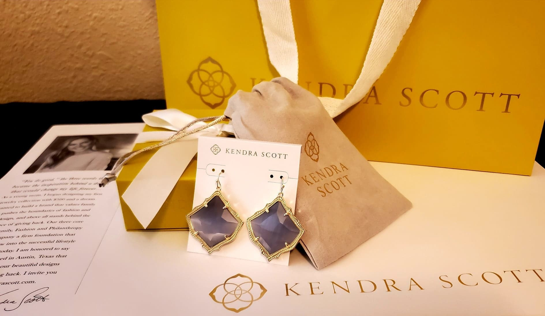 Beautiful Kendra Scott designer earrings in gold with purple gem stones.