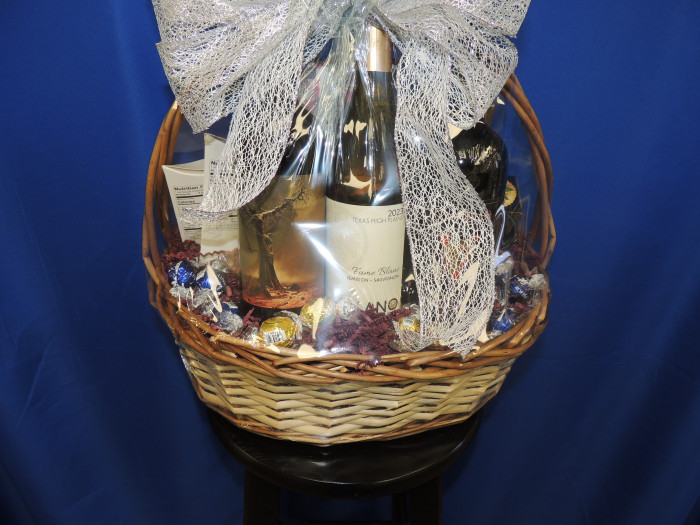 3 bottles of Llano Estacado Wine, Lindor Chocolates in the front; sausage, cheese spread, chocolate pretzel rods, sea salt caramel roca and crackers on the back.