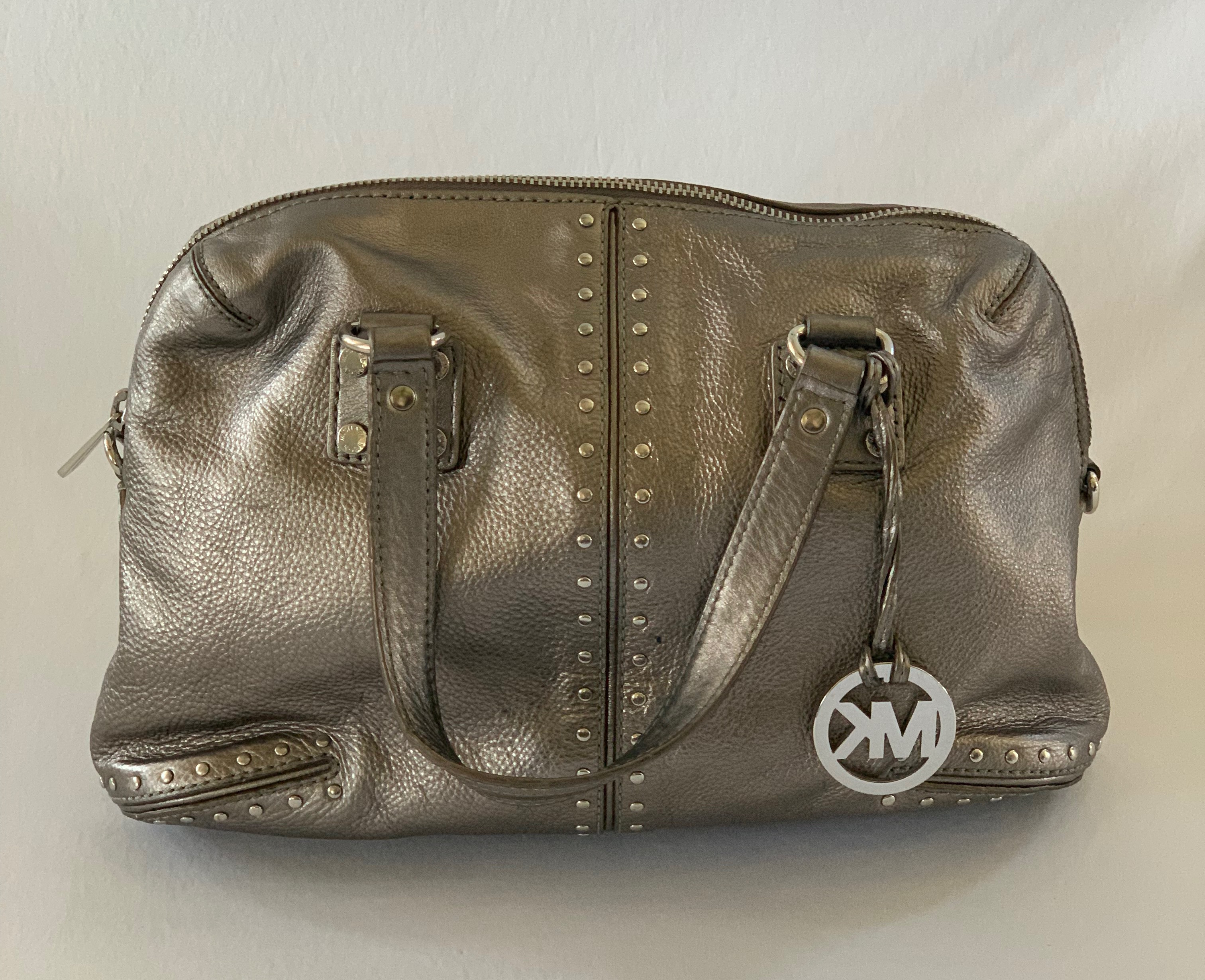 Metallic silver handbag with stud accents. Crossbody strap included. Ink stains on both interior and exterior.